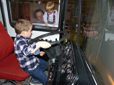 Řidič autobusu (M) pod dohledem hlavního revizora (F v okně).